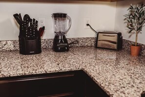 Kitchen counter with a blender, toaster, and knives, along with a potted plant.