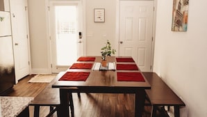 Ein Essbereich mit Holztisch und Bänken, einem Blumentopf und roten Platzsets.