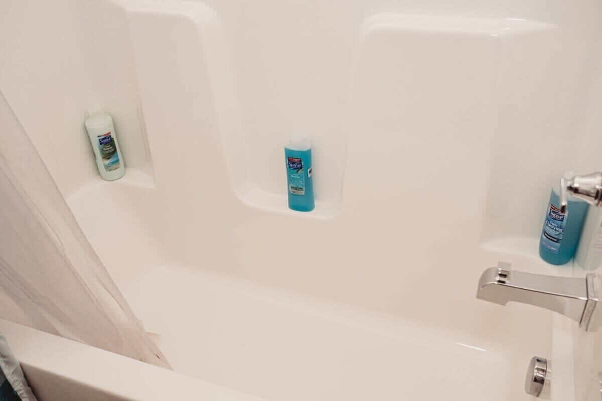 Une baignoire blanche avec deux bouteilles de savon liquide posées sur le bord.