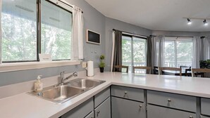 Cozinha moderna com uma ilha grande, pia de aço inoxidável e vista para o exterior.