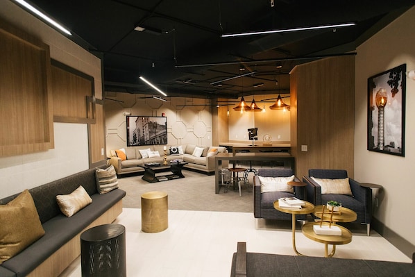 Una sala moderna con un sofá, sillones, una mesa baja y un comedor con sillas y una mesa.