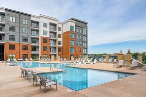 Un moderno edificio de apartamentos con piscina y sillones de descanso.