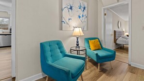 A room with two teal armchairs, a small table with a lamp, and a large abstract painting on the wall. - USC & Downtown Gem: Modern Family Home! (Columbia)