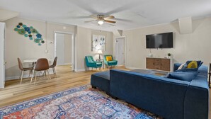 A living room with a blue sofa, a patterned rug, teal chairs, a wooden cabinet, and a ceiling fan. - USC & Downtown Gem: Modern Family Home! (Columbia)