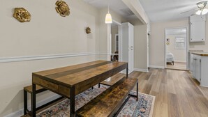 A spacious room with a long wooden table and benches, a hanging light fixture, and a patterned rug on the floor. - USC & Downtown Gem: Modern Family Home! (Columbia)