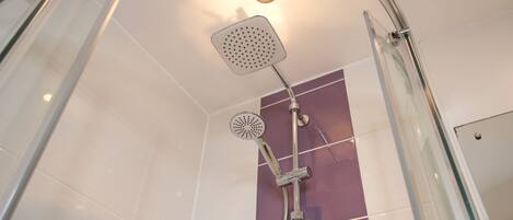 Une douche moderne dotée d’un pommeau de douche carré et d’un flexible de douche.