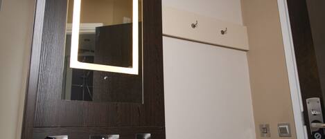 A bathroom with a wooden vanity, a mirror with a light, and a door with a sign.