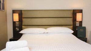 Ein ordentlich bezogenes Bett mit weißen Laken, zwei Kissen und je eine Nachttischlampe auf jeder Seite.