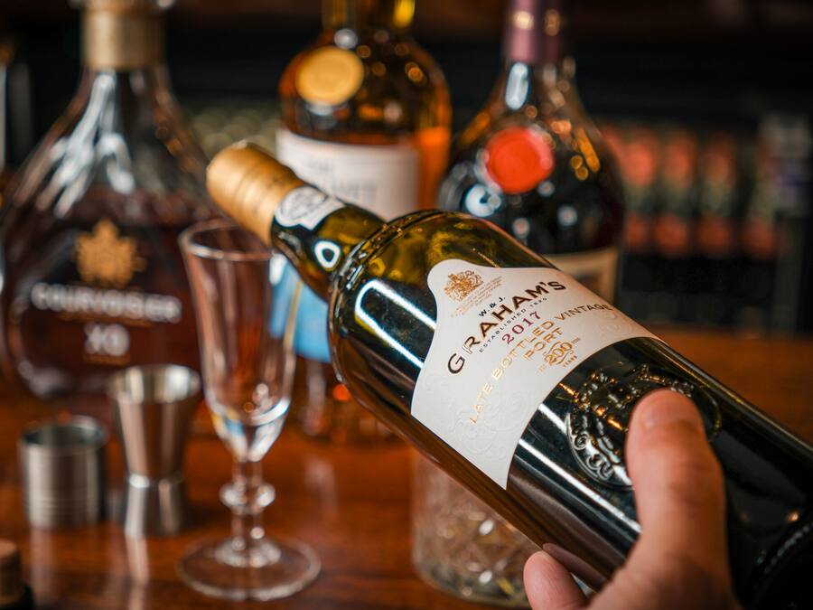 A hand holding a bottle of Graham's 2017 Late Harvest Port.