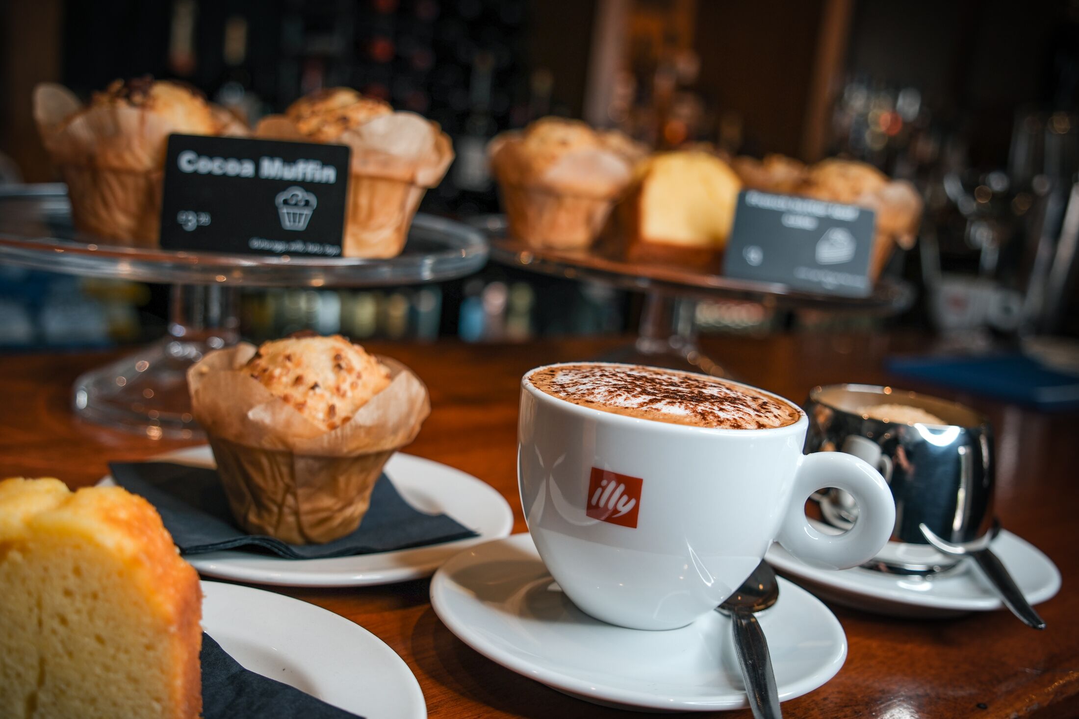 A coffee cup with a logo, a muffin, and a sign for 'Cocoa Muffin' on a tray.