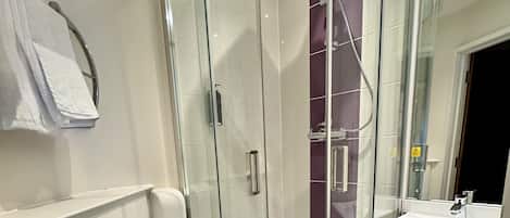 Ein modernes Badezimmer mit einer gläsernen Dusche, einer weißen Toilette und einem Waschbecken.