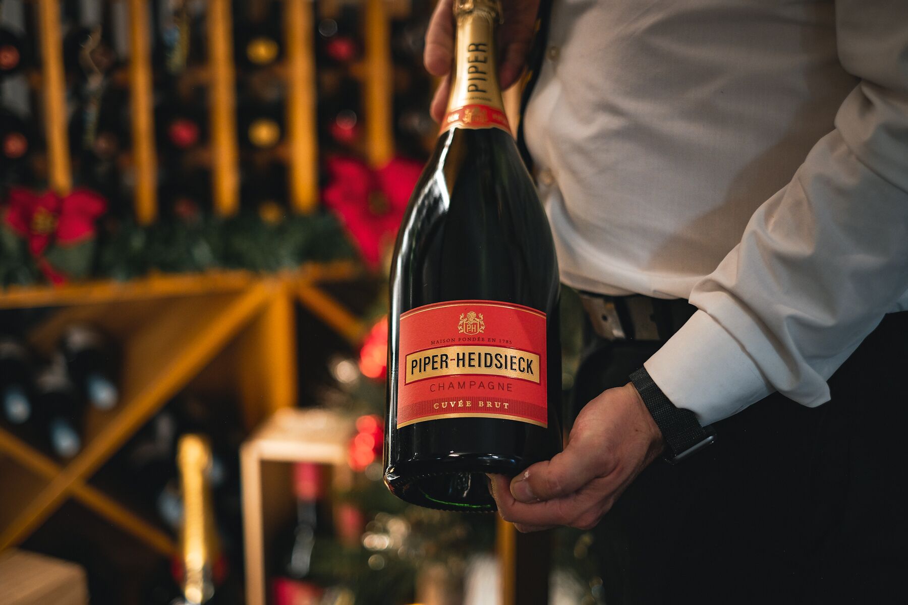 A person holding a bottle of Piper-Heidsieck Champagne.