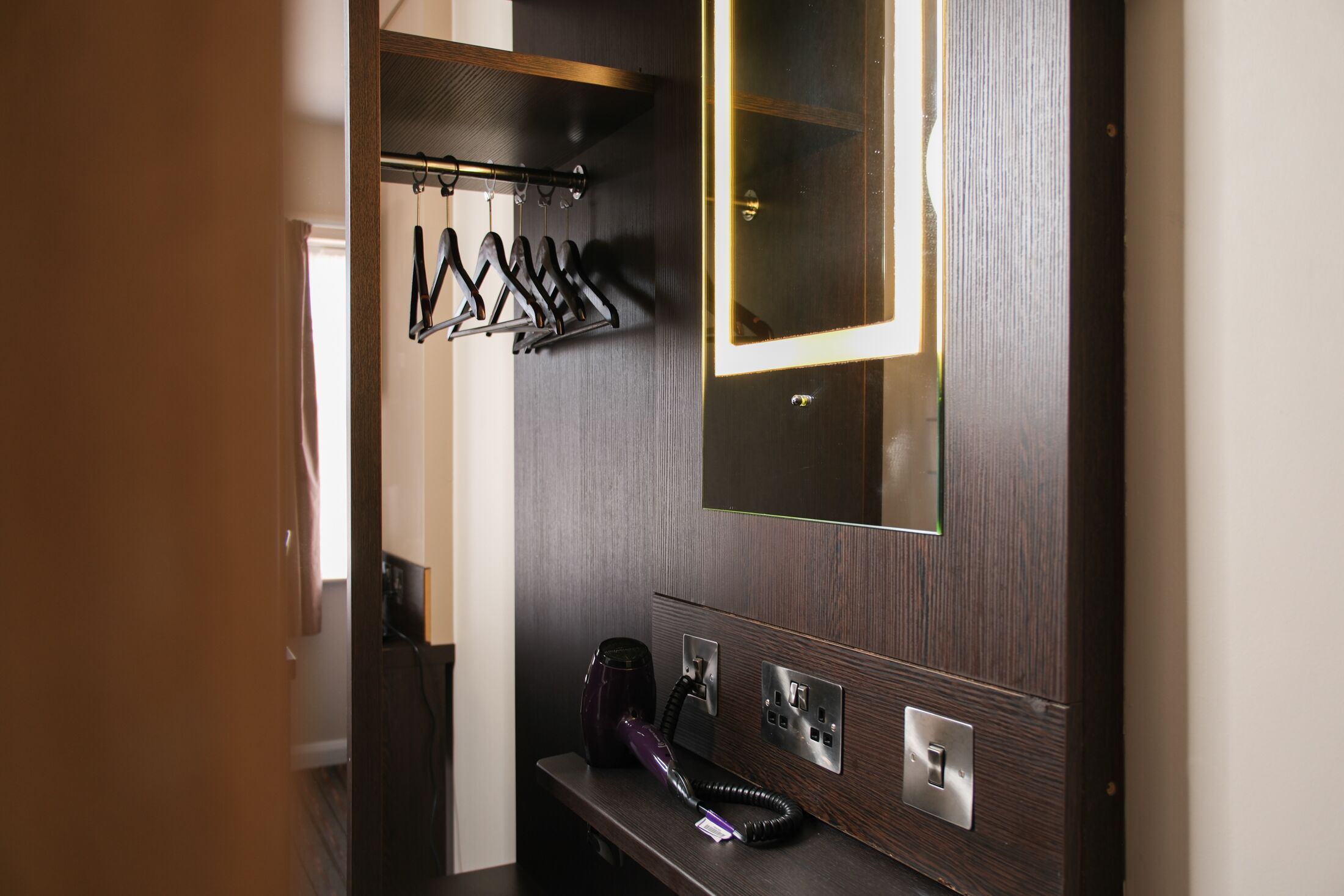 A modern bathroom with a dark wood vanity, a hairdryer, and a mirror above the counter.