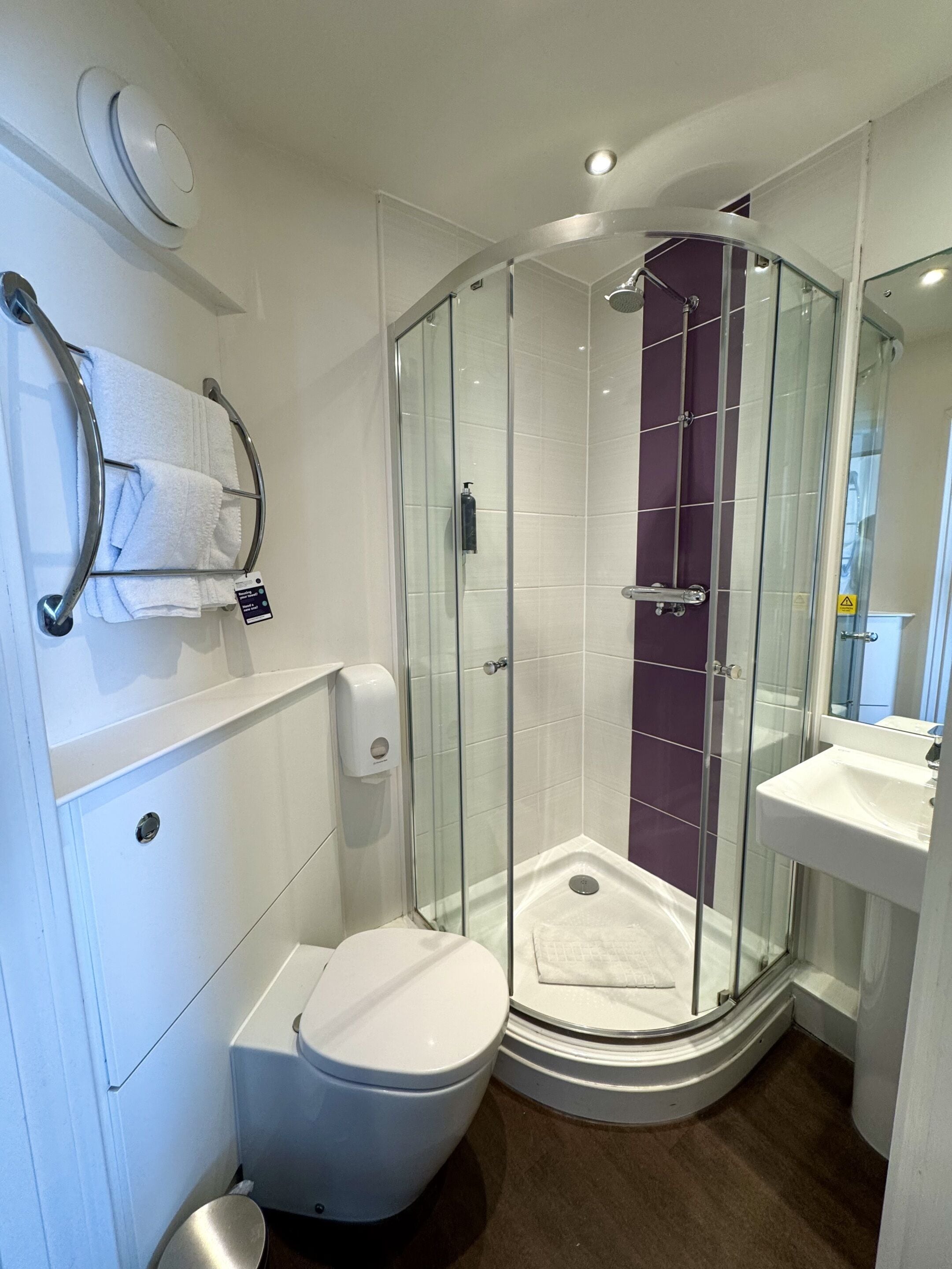 A modern bathroom with a glass-enclosed shower, a white toilet, and a sink.