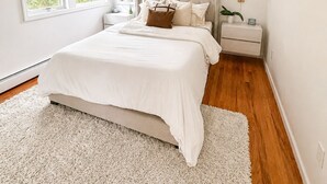 Camera da letto con un letto, un comodino, una ventola a soffitto e ampie finestre.