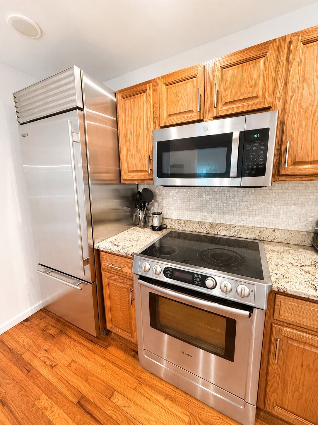 A kitchen with a stainless steel refrigerator, microwave, stove, and oven.