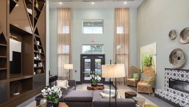 A spacious lobby with a sofa, chairs, a fireplace, and a bookshelf. - Landing | Incredible 1BD, Gym, Pool (Land O' Lakes)