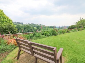 A bench in a garden with a view of a green landscape and hills in the distance. - Harcombe House Rooms - First Floor Double (Newton Abbot)