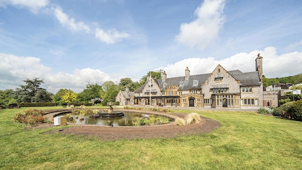 A large stone building with a pond in the foreground, surrounded by well-maintained lawns and trees. - Harcombe House Rooms - First Floor Double (Newton Abbot)