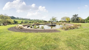 A landscaped garden with a central pond, a bench, and a variety of plants. - Harcombe House Rooms - First Floor Double (Newton Abbot)
