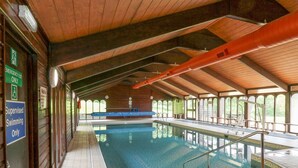 An indoor swimming pool with a tiled floor, a wooden ceiling, and a view of the outdoors through large windows. - Harcombe House Rooms - First Floor Double (Newton Abbot)