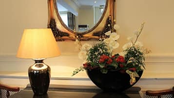 Une lampe et un arrangement floral sur une table, avec un miroir en arrière-plan.