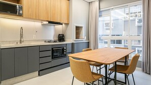 A modern kitchen with grey cabinets, a wooden dining table, and chairs. - Gastronomy | Hot Tub | Gym #TRINA04 (Florianópolis)