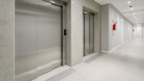A modern hallway with elevators and a fire extinguisher on the wall. - Gastronomy | Hot Tub | Gym #TRINA04 (Florianópolis)