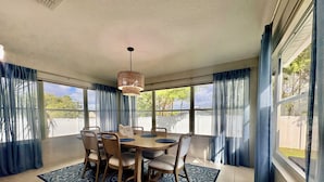 A dining area with a round table, chairs, a patterned rug, and a hanging light fixture.
