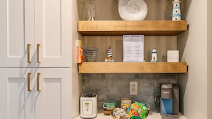 A kitchen with white cabinets, a wooden countertop, a coffee maker, and a decorative plate.