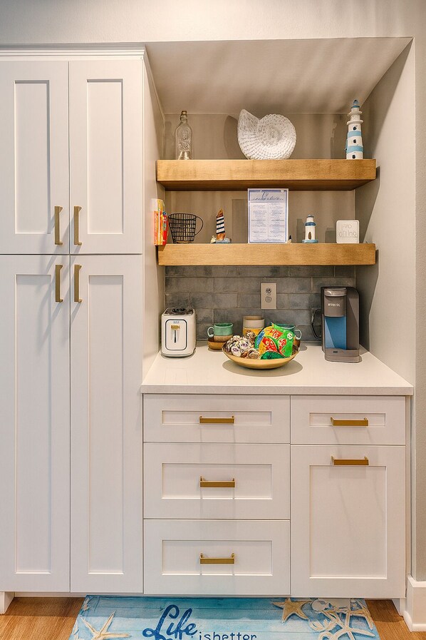 Een keuken met witte kastjes, een houten aanrecht, een koffiezetapparaat en een decoratief bord.