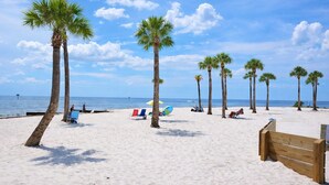 A beach with palm trees, beach chairs, and umbrellas.
