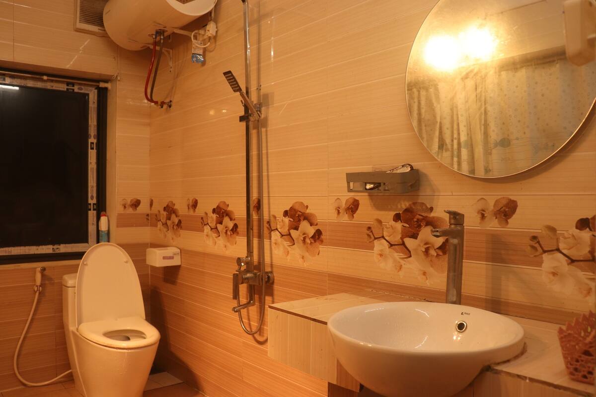 A bathroom with a toilet, sink, shower, and a mirror.