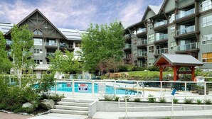 A modern hotel with a pool area, including a wooden deck and a gazebo. - Ski in/out Aspens 2BR - 3 HotTubs, Pool, Ski Valet, AC (Whistler)