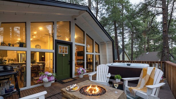 Eine gemütliche Außenterrasse mit Feuerstelle, weißen Adirondack-Stühlen und einem Whirlpool.