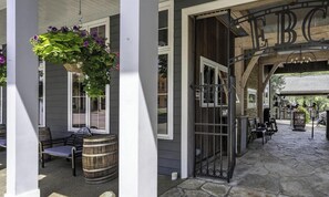 Un espacio exterior techado con una banca y una cesta de flores colgante.