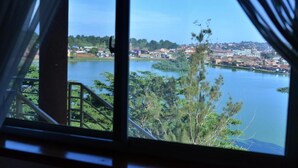 A view from a window overlooking a lake with buildings in the background. - Jevine Hotel (Kampala)