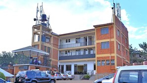 A multi-story building with a parking lot in front. - Jevine Hotel (Kampala)