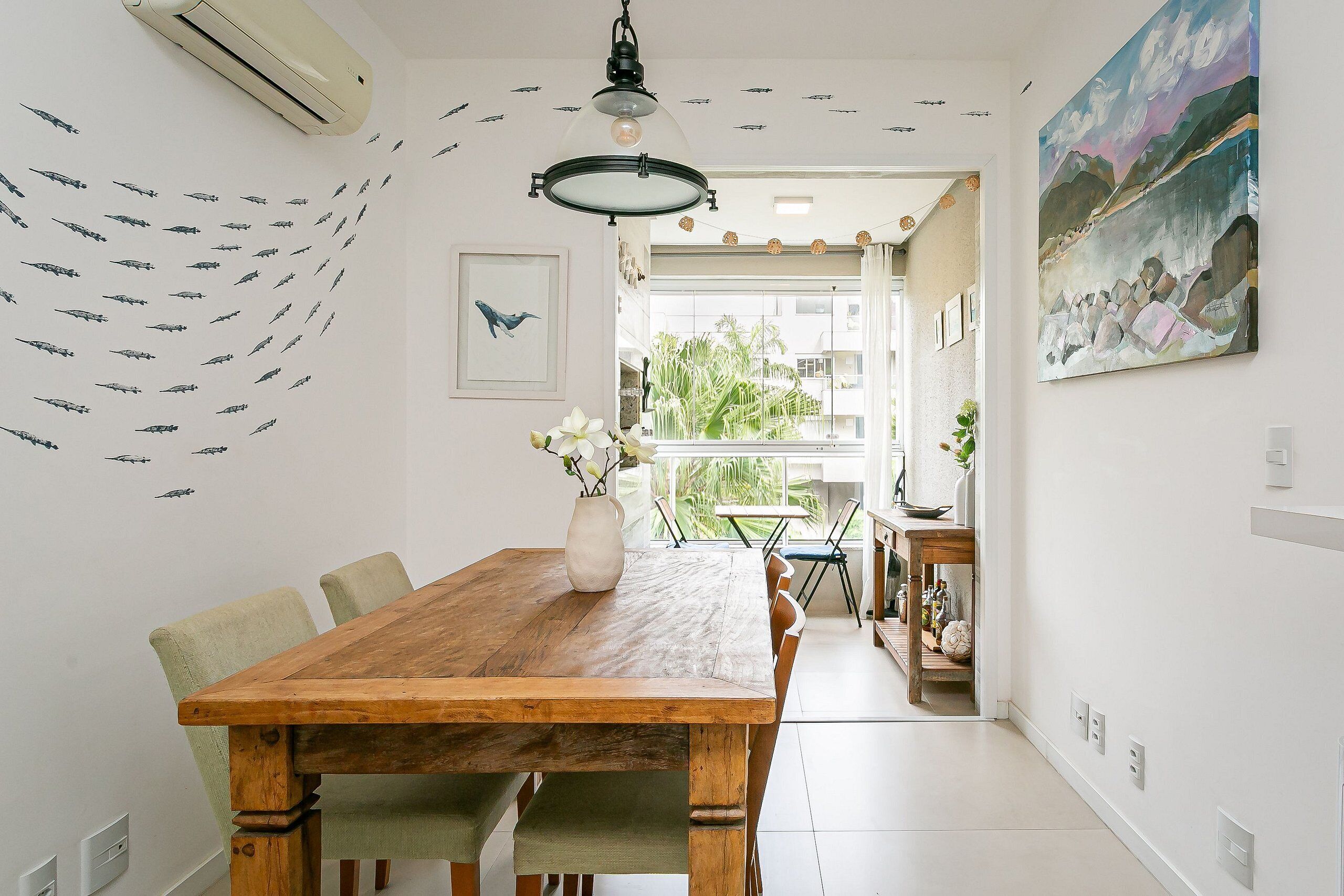 A dining area with a wooden table, chairs, a vase with flowers, and a ceiling fan.