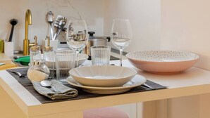 A neatly arranged dining area with a white table, clear glassware, and a pink bowl.