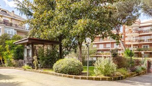 A courtyard with a gazebo, surrounded by lush greenery and a building with balconies.