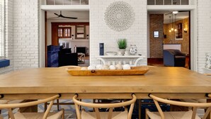 Een eethoek met een houten tafel en stoelen, een decoratief kunstwerk en uitzicht op een keuken en woonkamer.