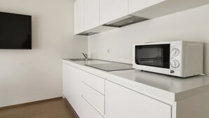 Een moderne keuken met witte kasten, een roestvrijstalen aanrecht en een ingebouwde magnetron.