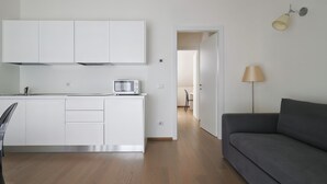 Een moderne keuken met witte kastjes, een ingebouwde magnetron en een eethoek met een tafel en stoelen.