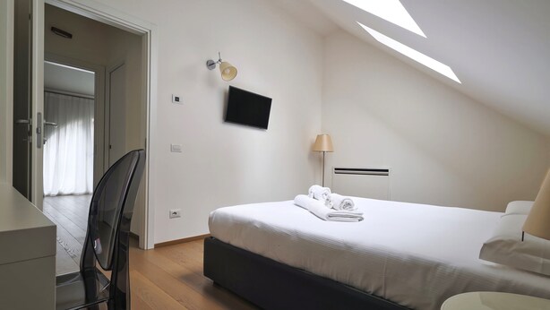 Een hotelkamer met een bed, een bureau, een stoel, een televisie en een lamp.
