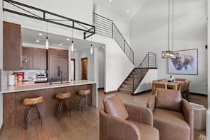 Una cocina moderna con armarios de madera, una barra y una escalera que lleva a un comedor.
