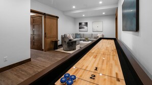 A modern living room with a shuffleboard table, a sofa, and a coffee table.