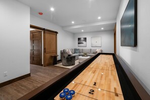 A modern living room with a shuffleboard table, a sofa, and a coffee table.