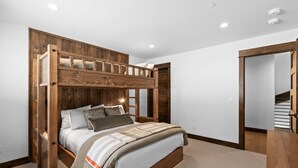 A bedroom with a bunk bed, a wooden headboard, and a carpeted floor.