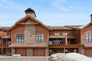 A multi-story log cabin with stone accents, multiple garage doors, and a balcony.